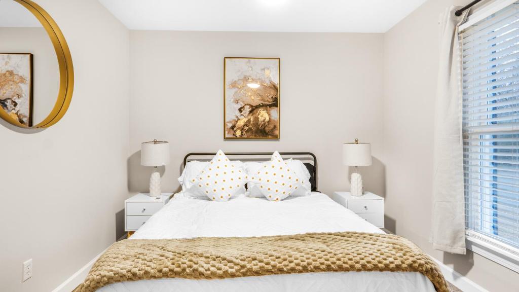 格林斯伯勒4-bedroom Bliss With Downtown Proximity的白色卧室配有带枕头和镜子的床