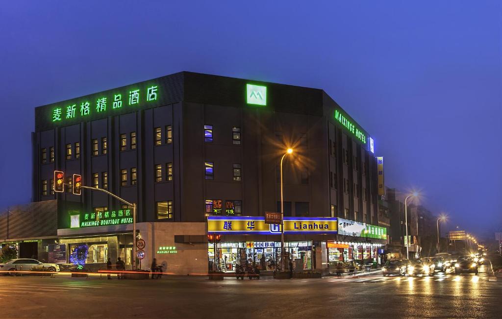 上海麦新格精品酒店川沙店的街道边有 ⁇ 虹灯标志的建筑物