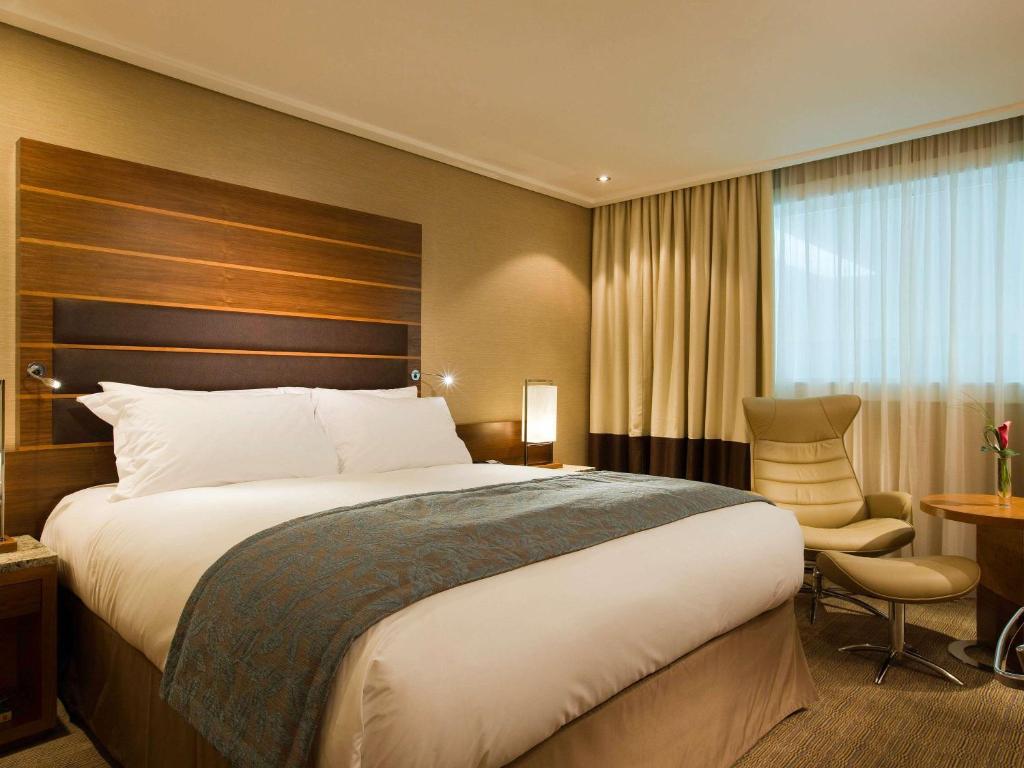 希灵登索菲特伦敦希斯罗酒店的酒店客房带一张大床和一把椅子