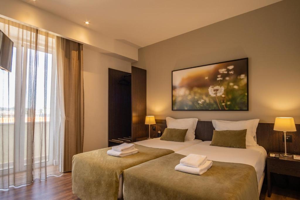 科英布拉河畔套房酒店的酒店客房设有两张床和大窗户。
