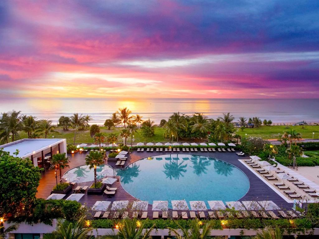 卡伦海滩Pullman Phuket Karon Beach Resort的享有带游泳池和椅子的度假村的空中景致