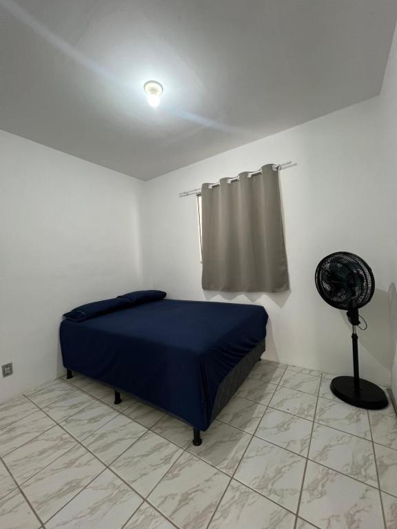 卡鲁阿鲁Nox Temporada - Casa com Piscina e Churrasqueira的一间卧室配有蓝色的床和风扇