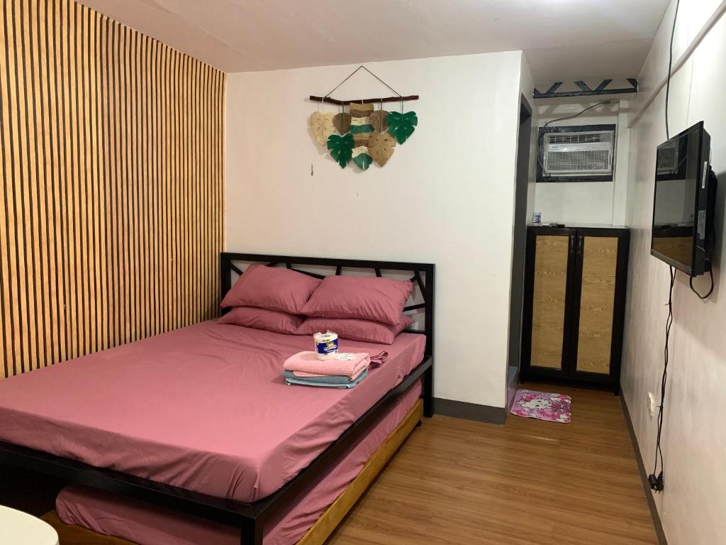 RomblonCapaclan Centro Private Room的一间小卧室,配有一张带粉红色床单的床