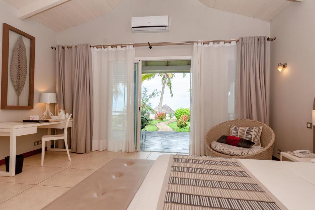 Ambondrona棕榈滩度假村及Spa的一间卧室配有一张床、一张书桌和一个窗户。