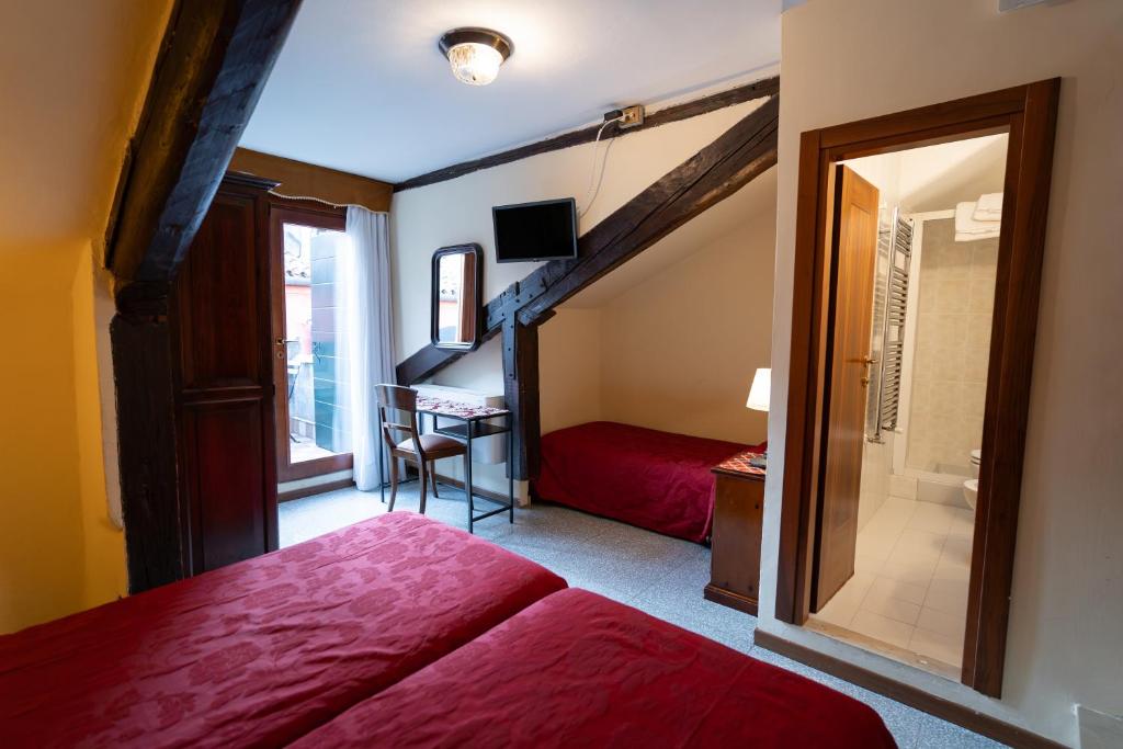 威尼斯蒂沃利酒店的一间卧室配有红色的床和一张书桌
