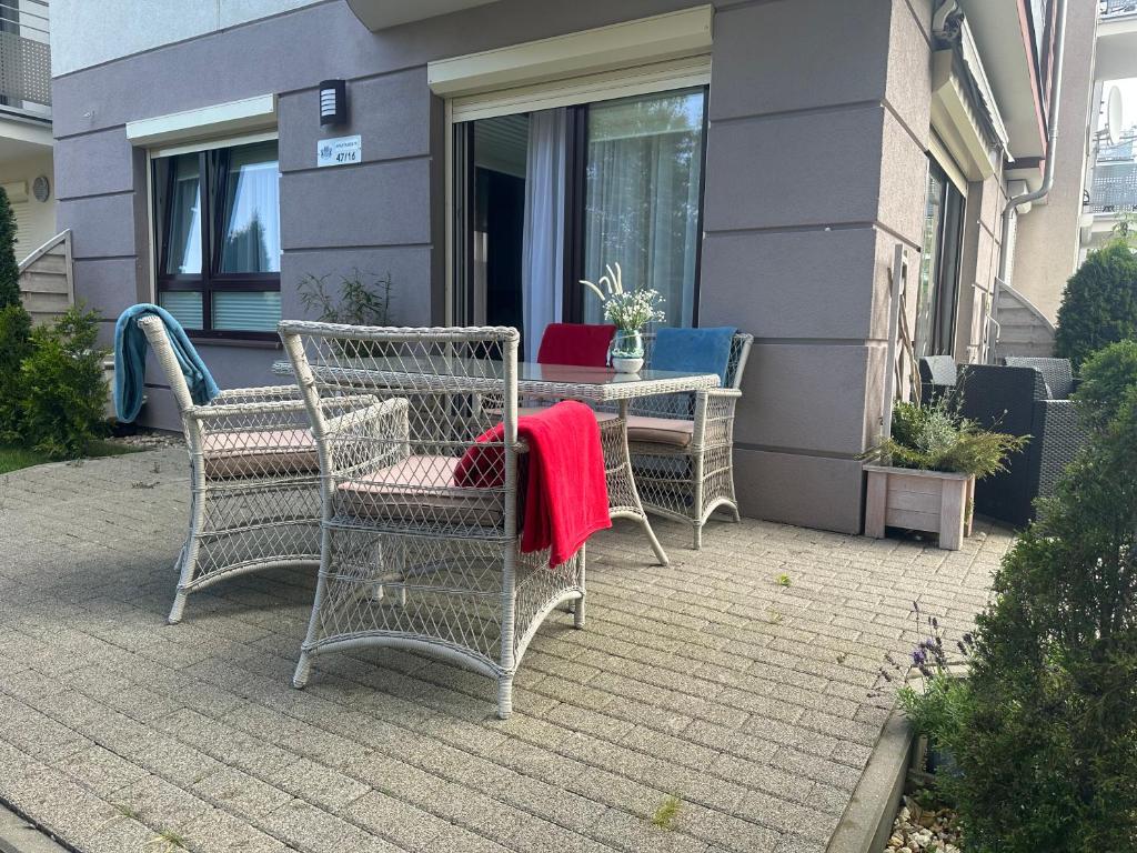 加茨比亚格拉Amko Style Apartamenty Nord 7 z prywatnym ogródkiem Willa Nord的庭院配有椅子和一张桌子及红色毯子