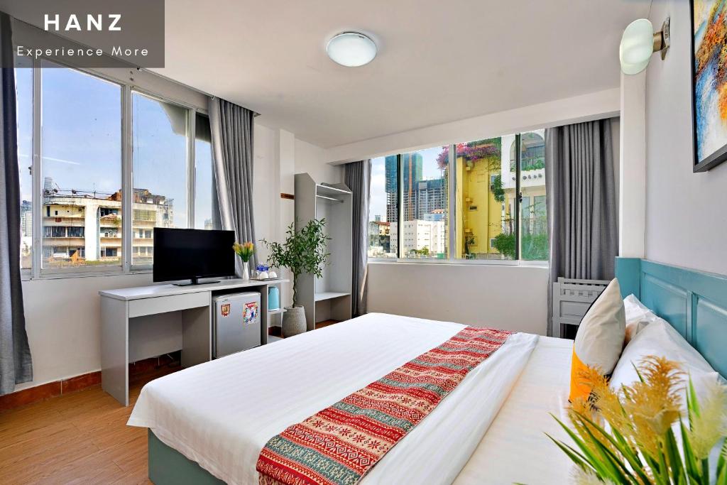胡志明市HANZ Hotel Bui Vien upstair MP ChillBAR的一间卧室配有一张床和一张书桌及电视