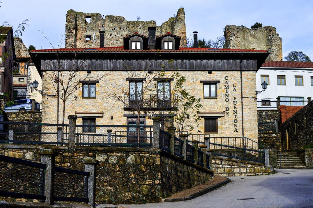 Cabrejas del Pinar斯提阿卡米诺德拉福恩特纳酒店的一座古老的石头建筑,后面是一座城堡