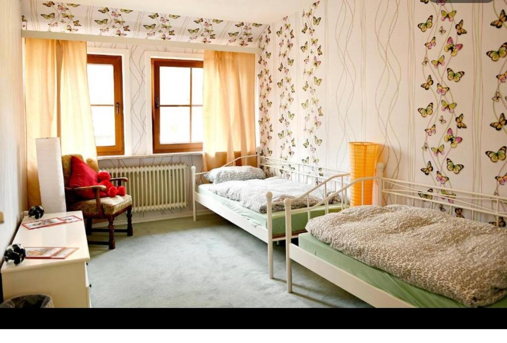 翁德洛Hotel am Naturschutzpark的一间卧室设有两张床、一把椅子和窗户。