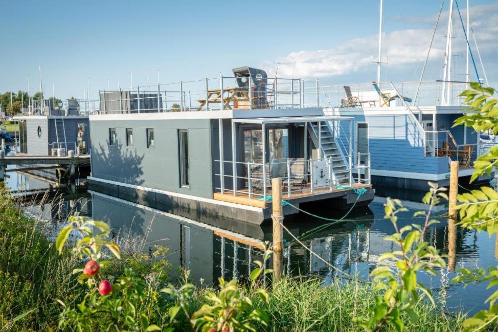 TorrigHausboot Rán mit Dachterrasse in Kragenæs auf Lolland/DK的船屋停靠在水面上的码头