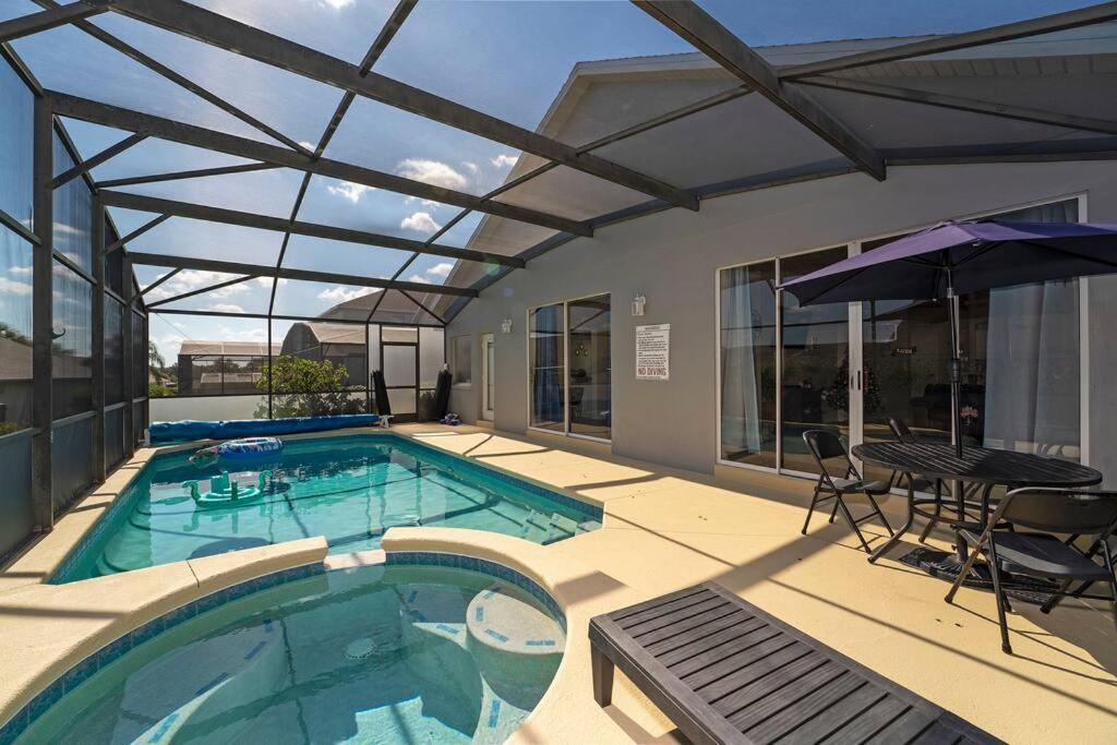 奥兰多Poolside Orlando Oasis的一个带桌椅和遮阳伞的游泳池