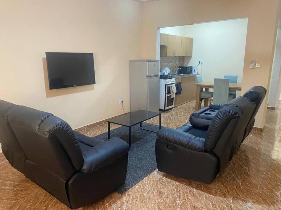 BrikamaIzzy Guest House的客厅配有两张真皮沙发和一台电视机