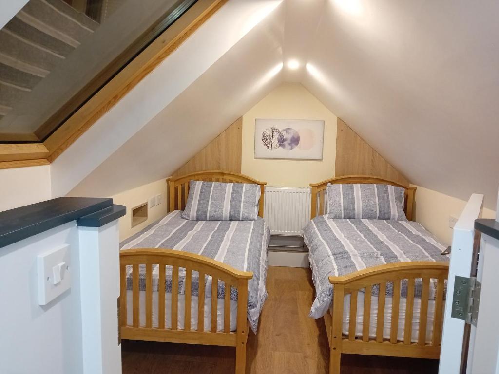 卡洛Fenniscourt Cottage的阁楼间设有两张床,设有楼梯