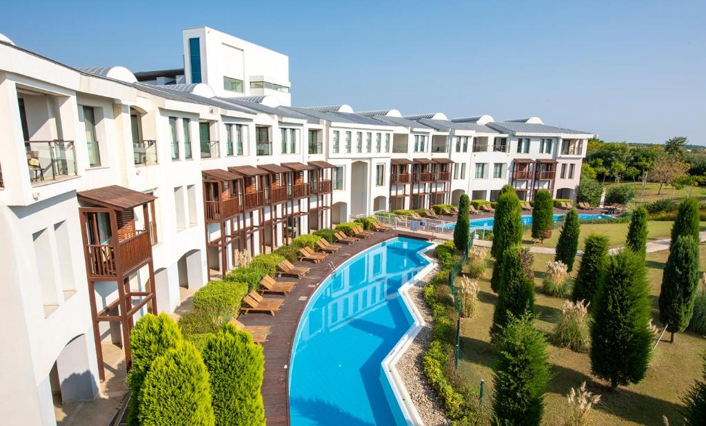 DenizyakaLykia World Links Golf Antalya的公寓大楼设有游泳池和树木