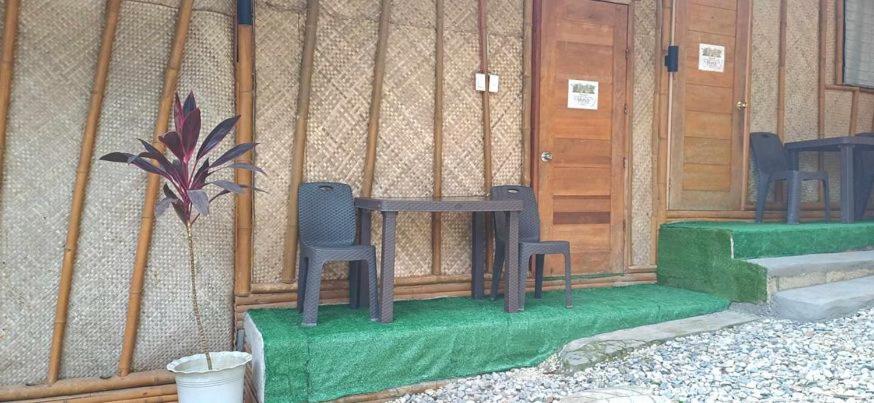 邦劳Ecostay Panglao Resort Hotel的一间位于大楼前的带两把椅子和一张桌子的房间