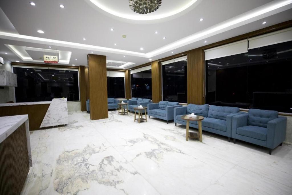 利雅德علم الفريدة للوحدات السكنية المفروشة Alam Faridah Hotel的大堂设有蓝色的沙发、桌子和窗户。
