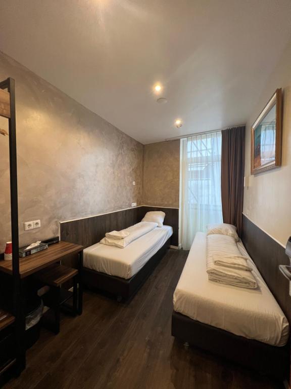 阿姆斯特丹Dam Hotel的酒店客房,设有两张床和镜子