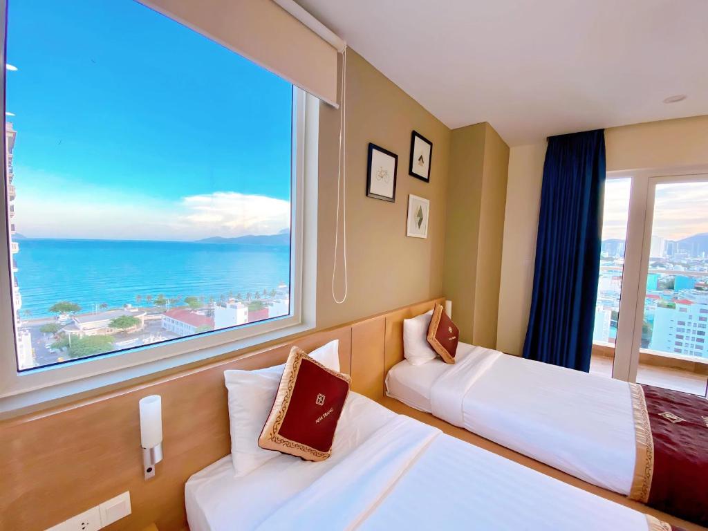 芽庄Gibson Hotel Nha Trang的酒店客房设有两张床和大窗户。