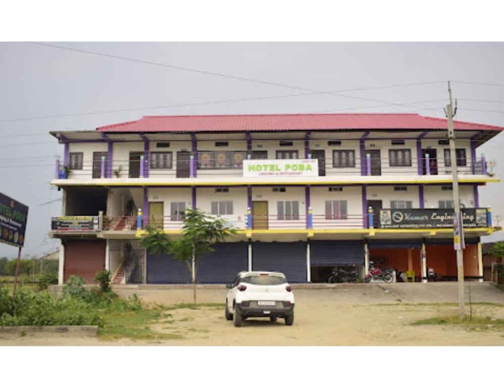 Hotel Poba, Jonai, Assam的停在大楼前的白色汽车
