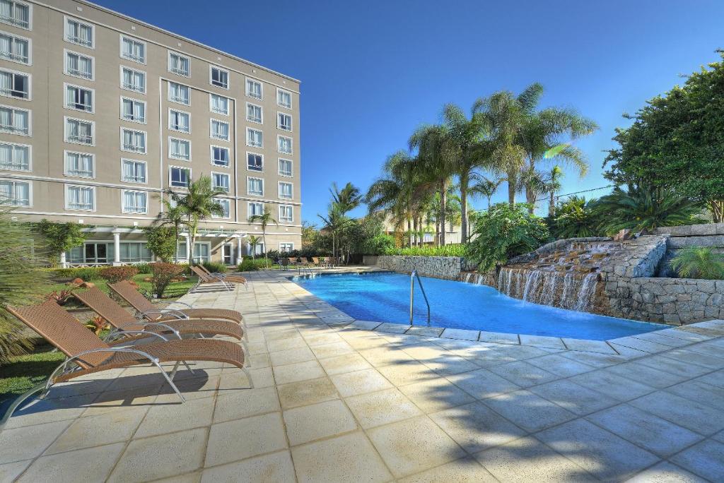 阿雷格里港阿雷格里港德维尔总理酒店的一座建筑前的带椅子和游泳池的酒店