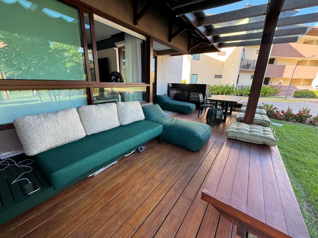 普拉亚多斯卡内罗斯Flat+deck ao lado da igrejinha的木制甲板上配有绿色沙发的庭院