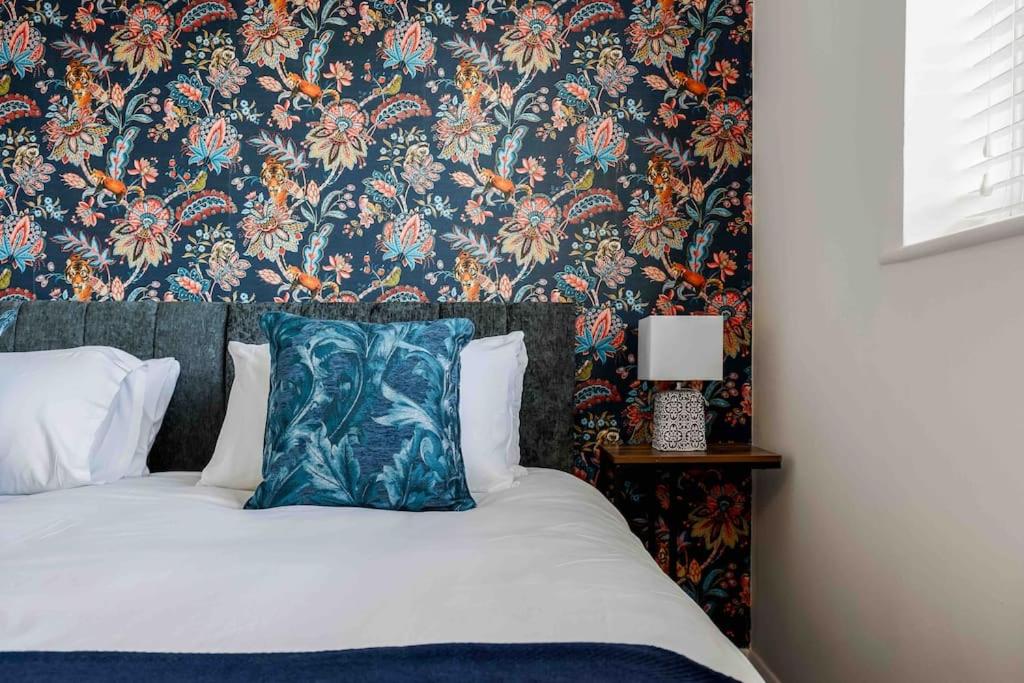 伯恩茅斯2 bedroom House-Driveway - Bournemouth Hospital - Long Stay Discounts - Lima Apartments Ltd的一间卧室配有一张带花卉壁纸的床
