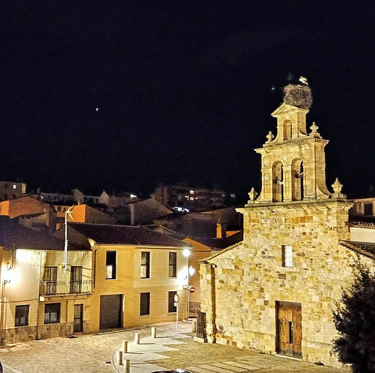 萨莫拉Mirador de las cigüeñas的一座古老的石头建筑,晚上有钟楼