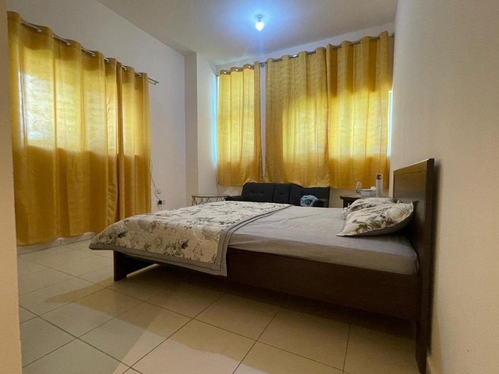 阿吉曼Holiday Home Master bed room in Ajman city UAE的一间卧室配有一张带黄色窗帘的大床