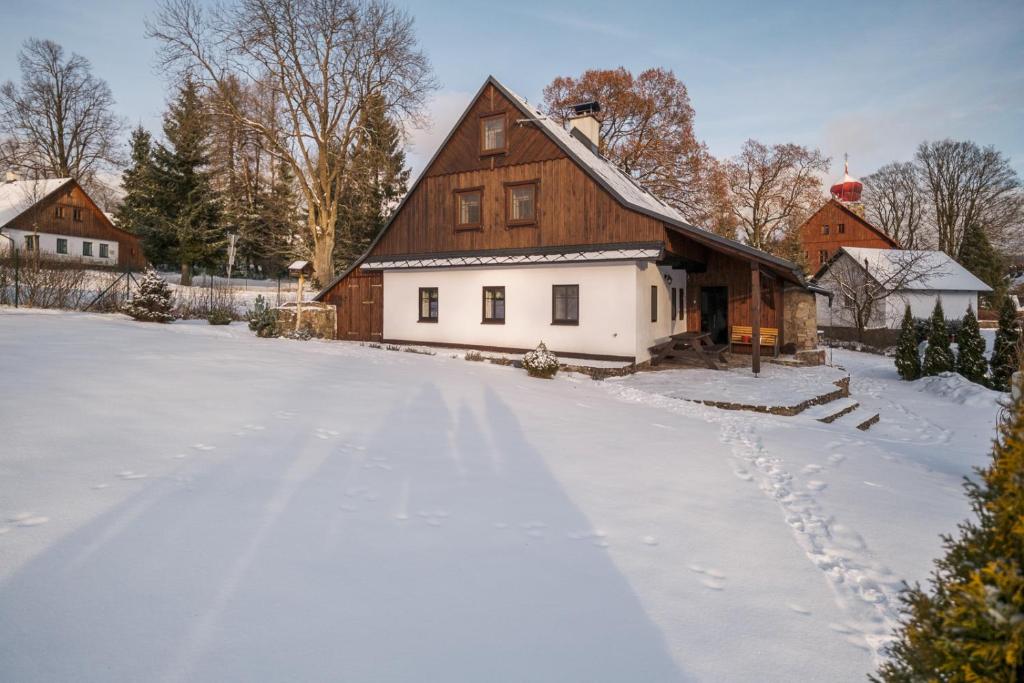 日茄基Chalupa U Křížku Říčky v Orlických horách的一座有房子和谷仓的雪地覆盖的院子