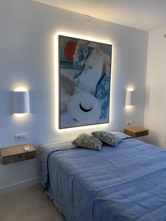卡拉布兰卡apartamento nº 7 cala pregonda的卧室配有一张蓝色的床,墙上挂着一幅画
