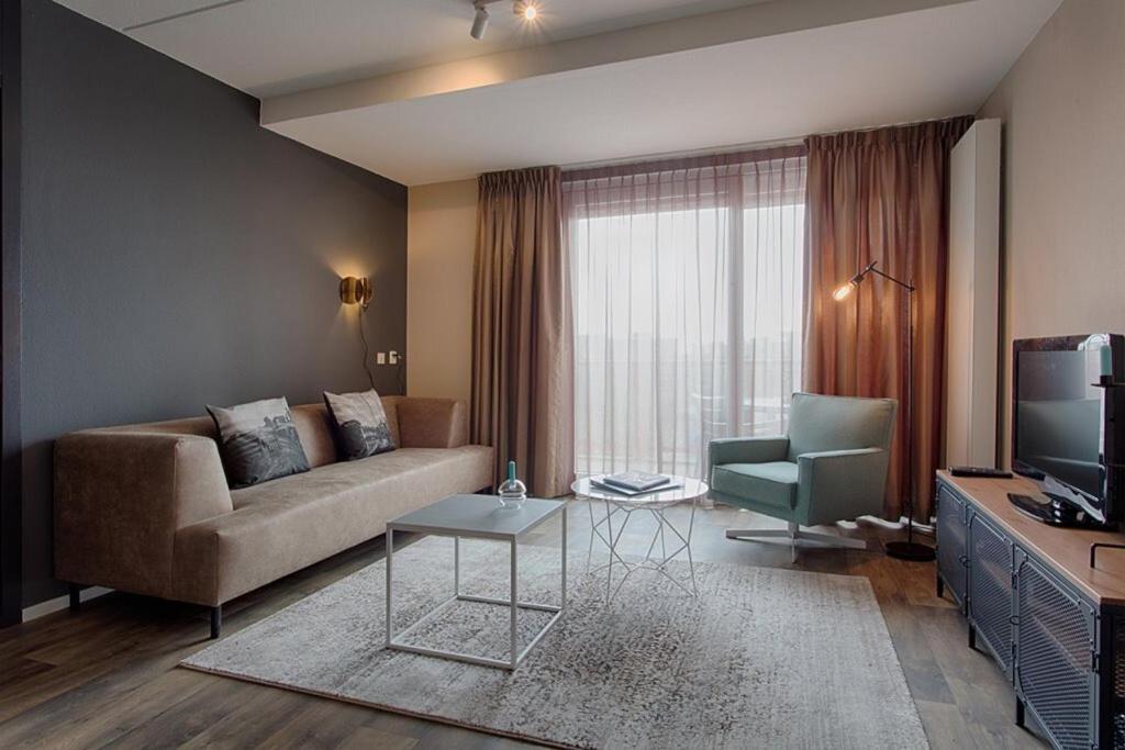 玛库姆Zuiderzeestate 35, prachtig appartement aan het IJsselmeer的带沙发和电视的客厅