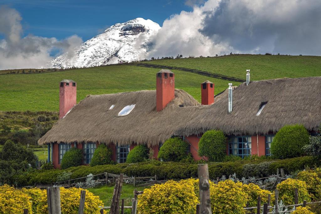MachachiHacienda El Porvenir by Tierra del Volcan的茅草屋顶和雪覆盖的山