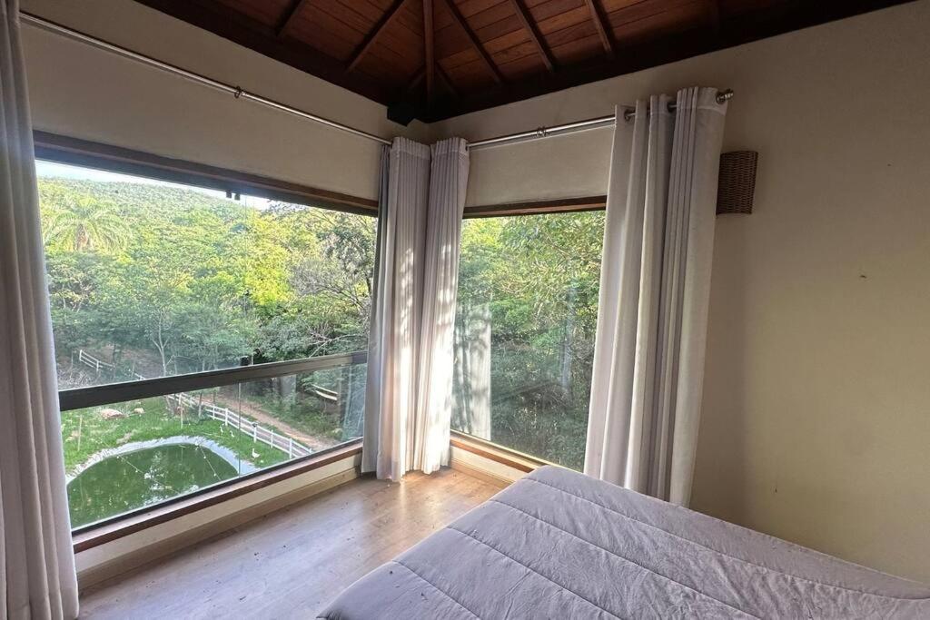 西波山Chalé Canto da Montanha的一间卧室设有一张床和一个大窗户