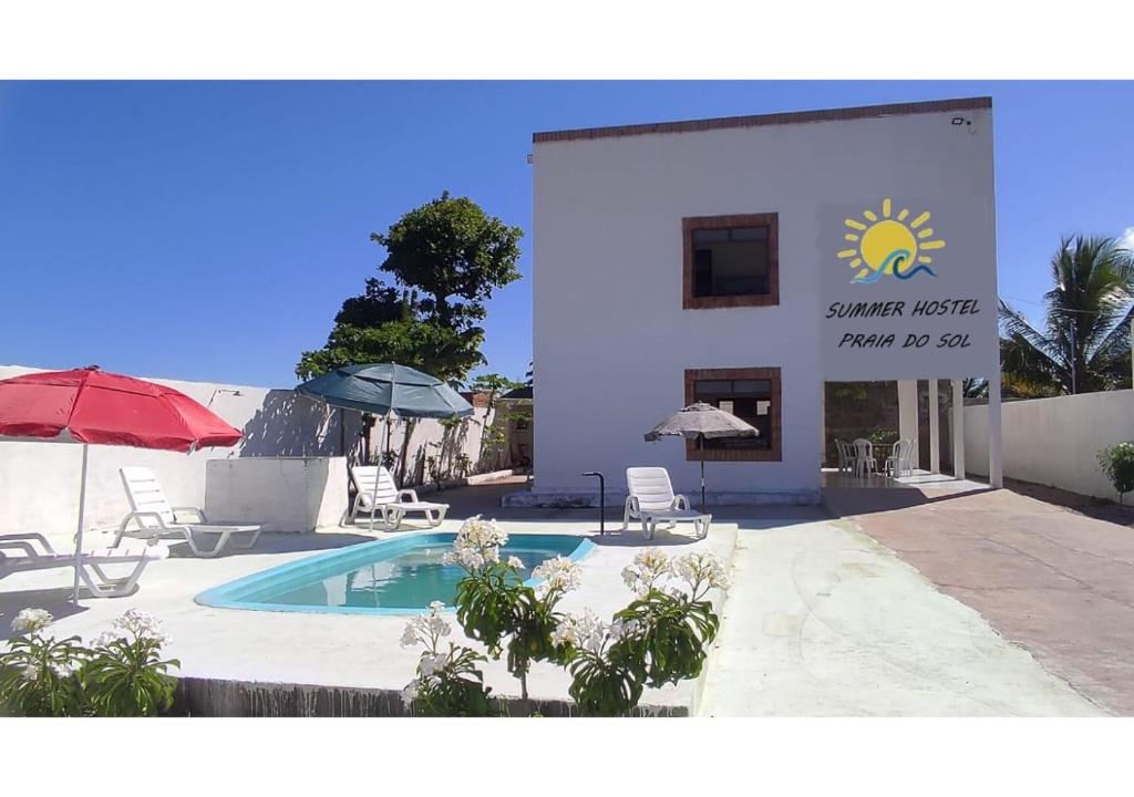 若昂佩索阿Hostel Summer Praia do Sol的一座带游泳池、椅子和遮阳伞的建筑