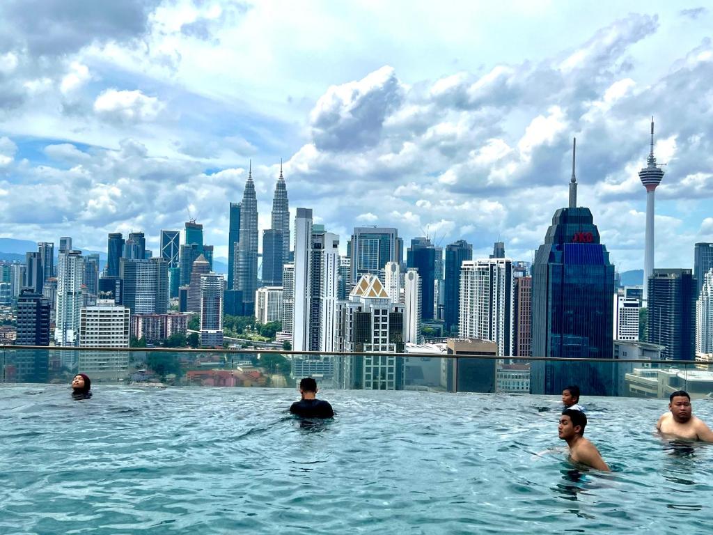 吉隆坡Regalia service suites klcc skypool的一群人在一座城市天际线的无边泳池游泳