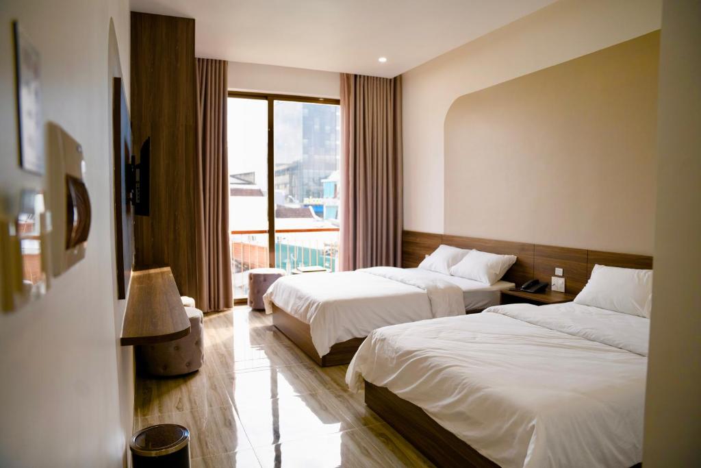 广义Tuyet Suong Hotel的酒店客房设有两张床和窗户。