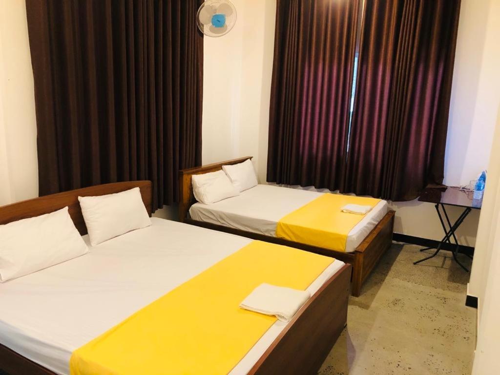 IbbagomuwaLotus cool hotel and restaurant的酒店客房设有两张床和窗户。