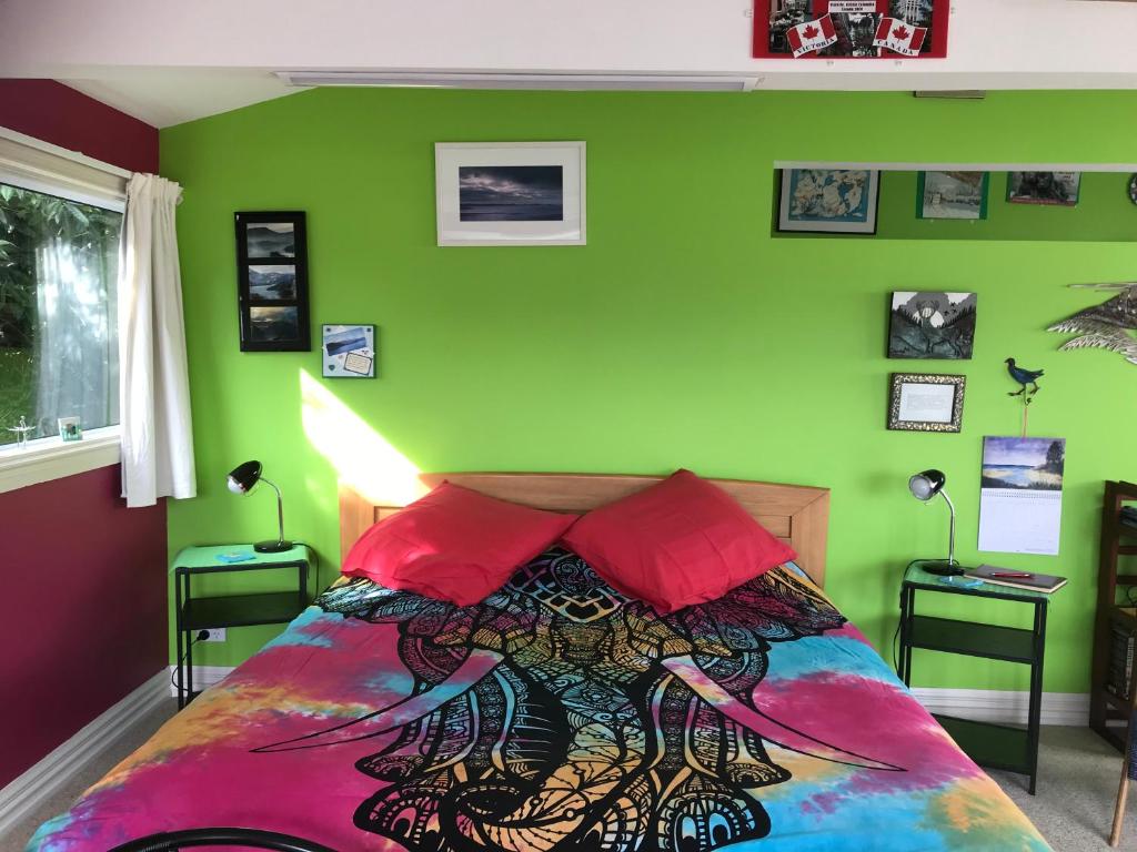 但尼丁Piringa的一间卧室设有绿色的墙壁和一张带红色枕头的床