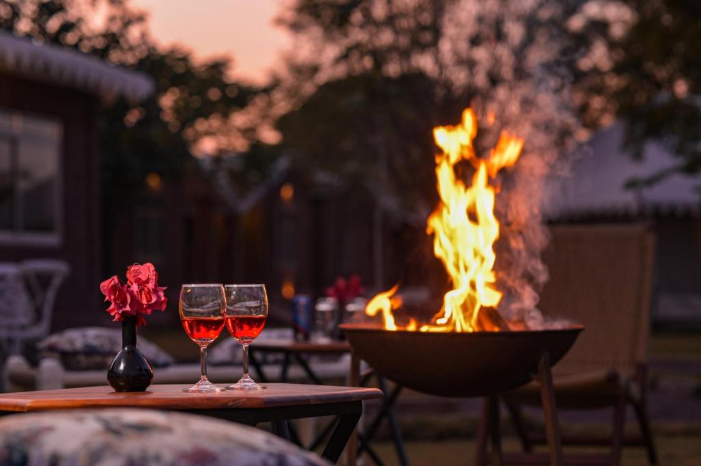 焦特布尔Impian Resorts的火坑旁桌子上放两杯葡萄酒