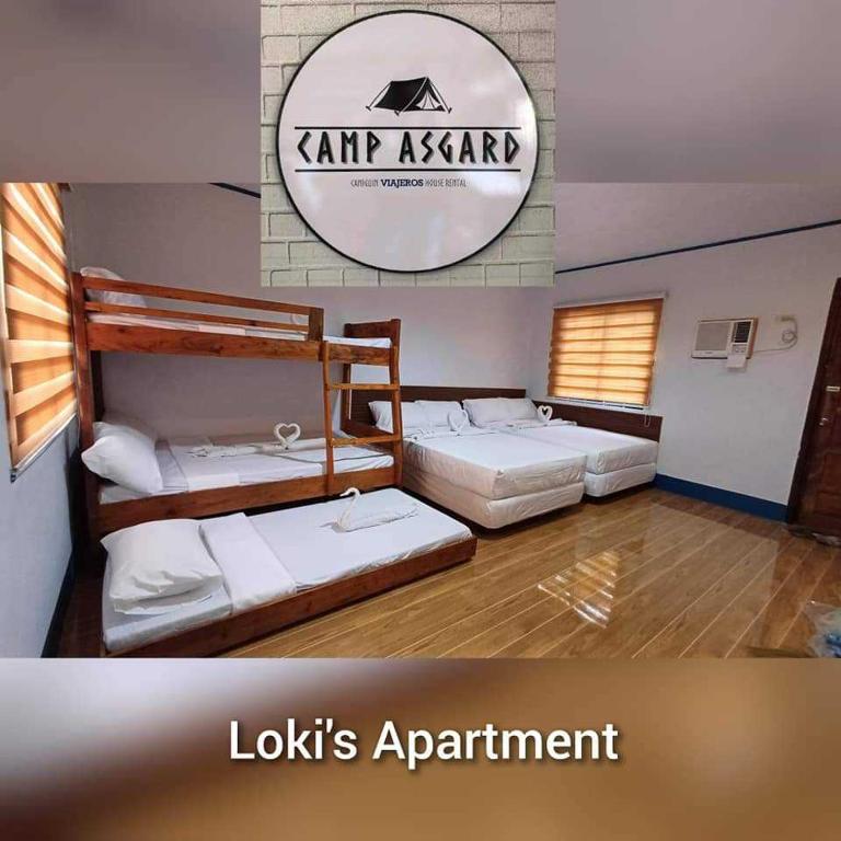 CatarmanLOKI'S APARTMENT的一间设有三张床的房间和一个读取外观设计公寓的标志
