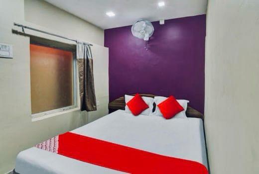 kolkataHOTEL AIRPORT HEAVEN的一间卧室配有红色和白色枕头的床
