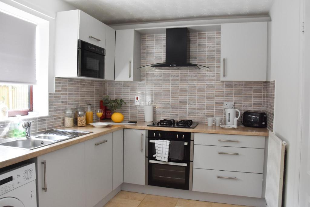 诺里奇Greenfield House的厨房配有白色橱柜和炉灶烤箱。