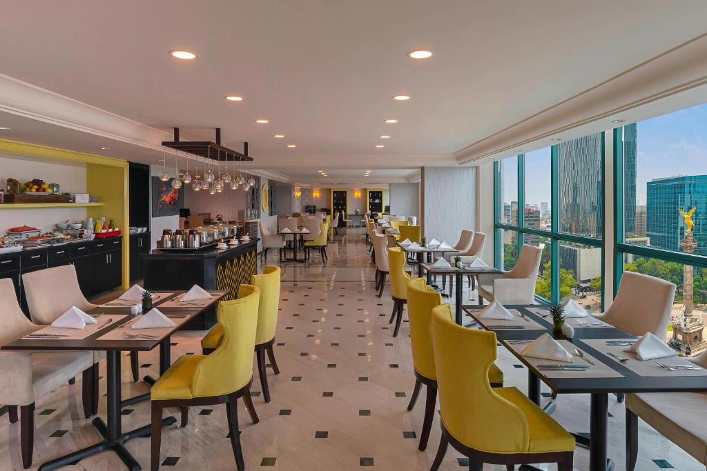 墨西哥城玛利亚伊莎贝尔墨西哥城喜来登酒店的餐厅设有黄色的椅子和桌子以及窗户。