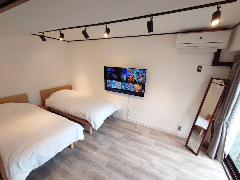 东京NIYS apartments 53 type的一间卧室设有两张床,墙上配有电视。