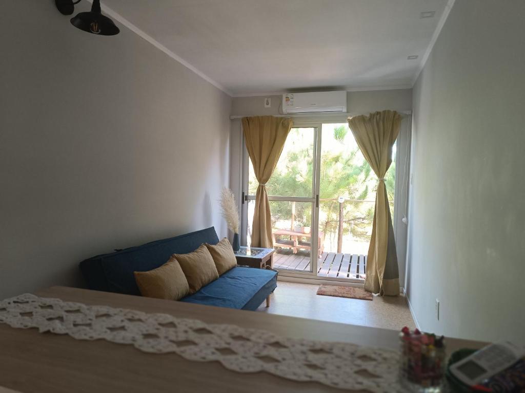 海岸城Frente a la playa en El Pinar的客厅设有蓝色的沙发和大窗户