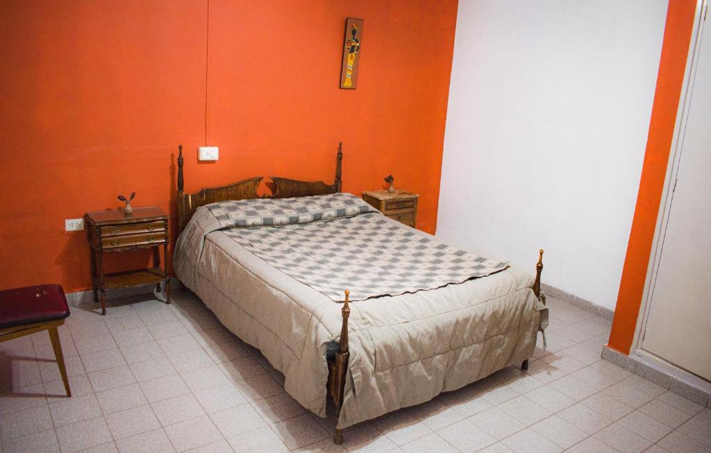 瓜伊马延RHOMBUS HOSPEDAJE Y HABITACIONES的一间卧室设有一张床和橙色的墙壁