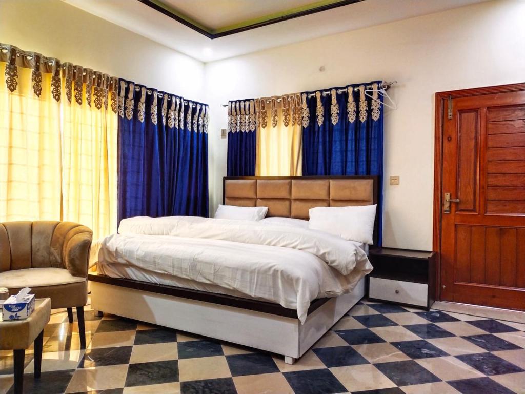 伊斯兰堡AK House Guest House的一间卧室配有一张带蓝色窗帘的床和一把椅子