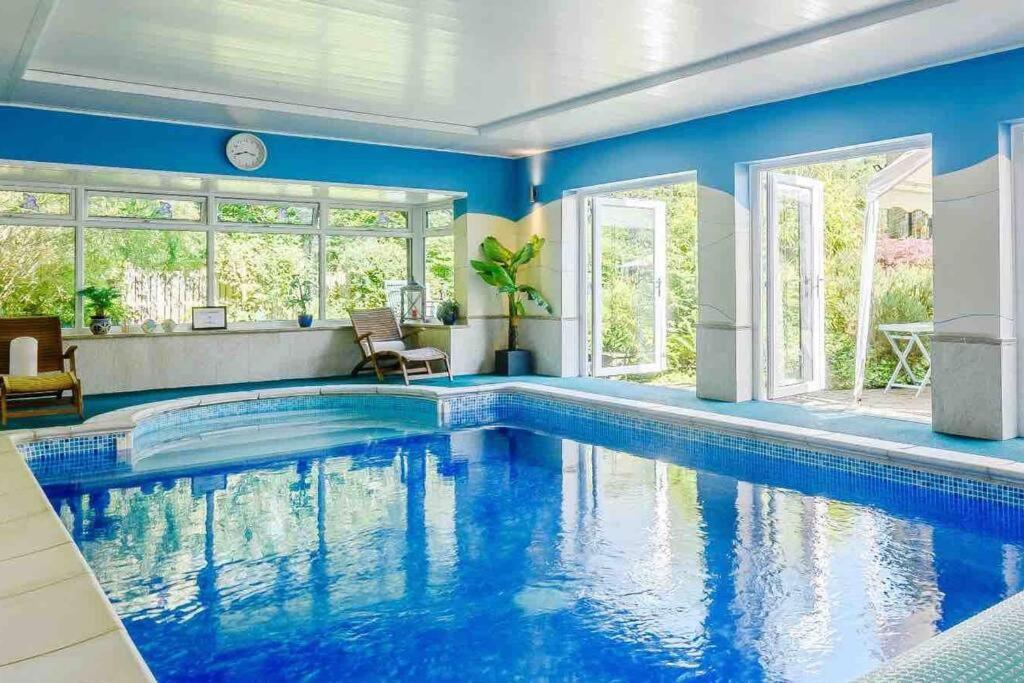 LydbrookMireystock Indoor Pool, Games Bar, Spa Steam Cabin的一座游泳池,位于一栋拥有蓝色墙壁和窗户的房屋内