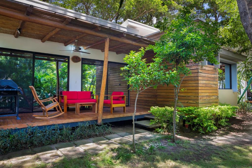 IguanaCasa Papaya - Eco Casita Phase 1-1的房屋设有红色椅子的木制甲板