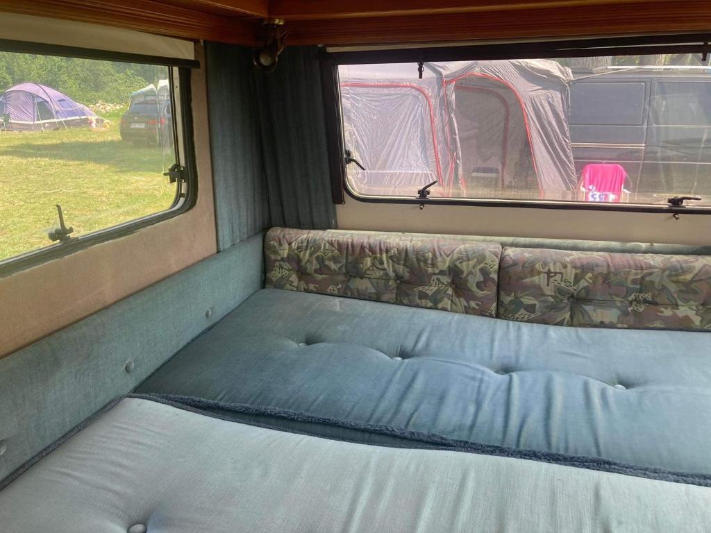 姆热日诺Camping Rogowo的拖车后面的一张带两个窗户的床